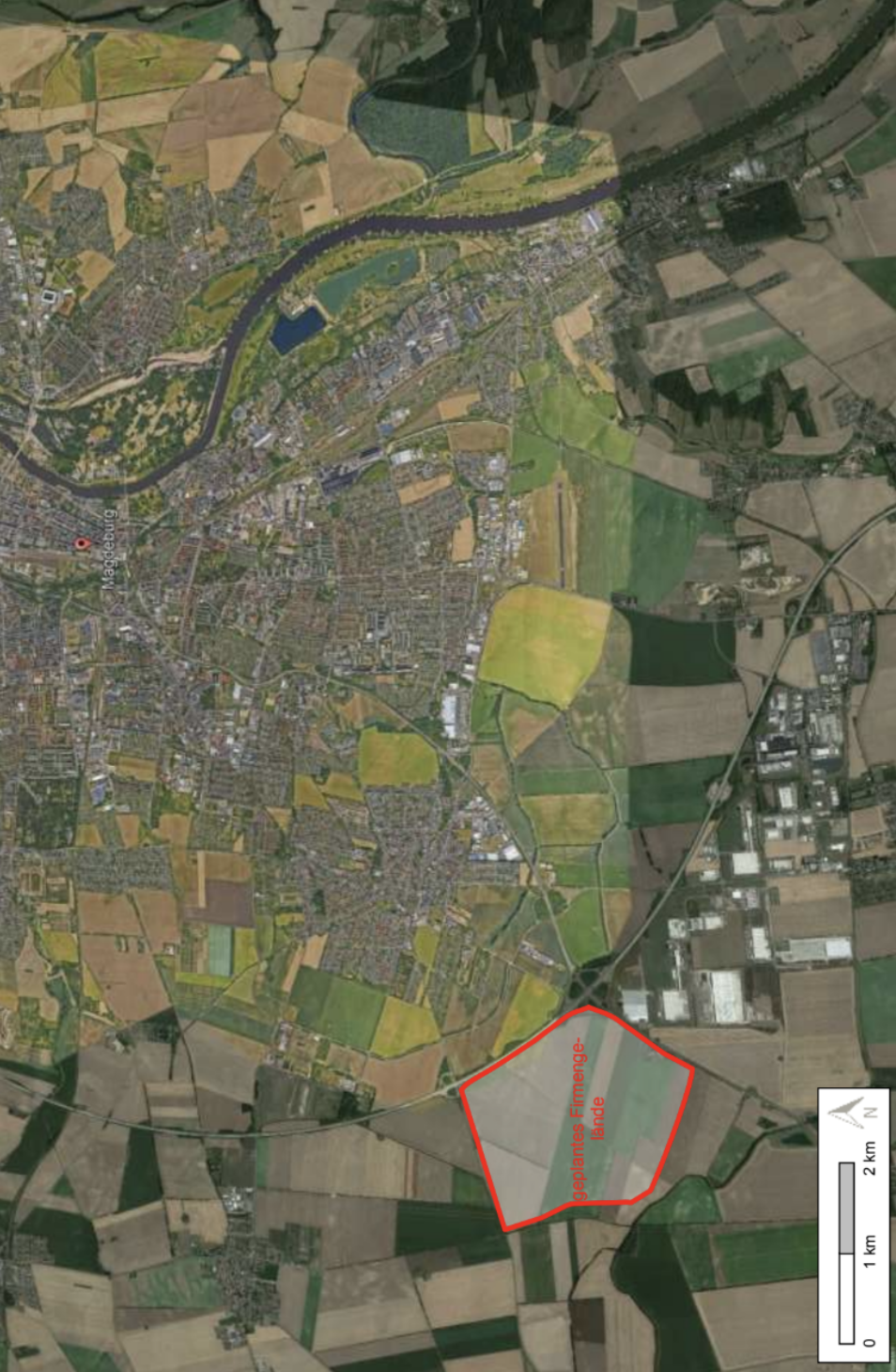 Luftbild einer Stadt mit Fluss, Feldern und einem rot markierten Gebiet (geplantes Firmengelände)